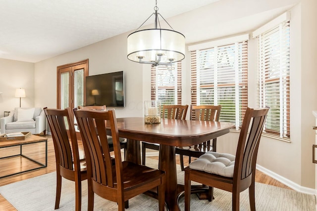 dining area featuring light wood-style flooring, baseboards, and an inviting chandelier