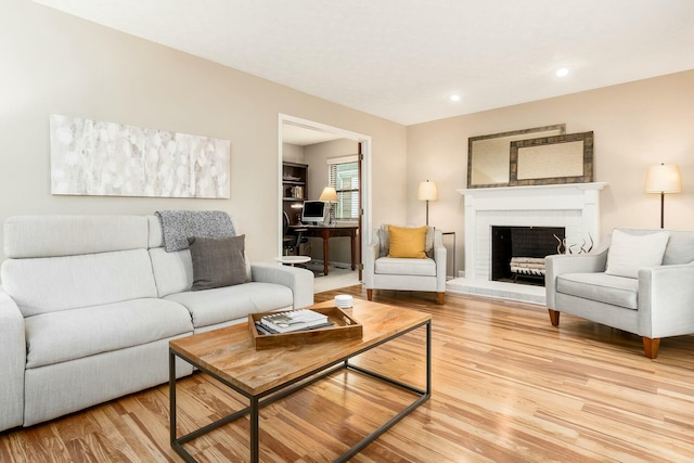 living room with recessed lighting, light wood-style flooring, and a brick fireplace