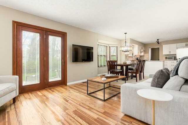 living area with light wood finished floors, baseboards, and a notable chandelier
