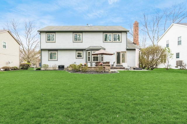 back of house featuring a chimney, a yard, central AC, and a patio