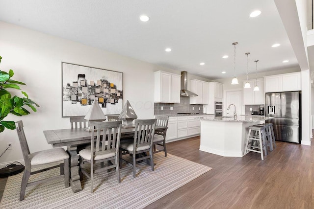 2418 Home Rd, Powell, OH 43065 - kitchen with stainless steel appliances, wall chimney exhaust hood, a center island with sink, tasteful backsplash, and dark wood-style flooring