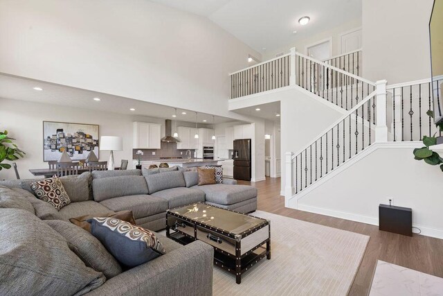 2418 Home Rd, Powell, OH 43065 - living area featuring light wood-style flooring, baseboards, a towering ceiling, recessed lighting, and stairs