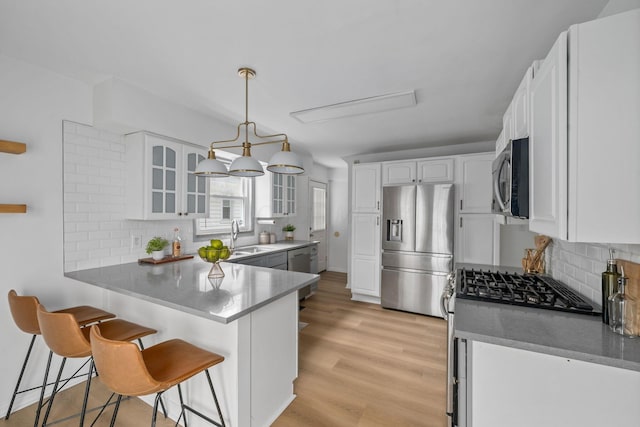 876 Palmer Rd, Columbus, OH 43212 - kitchen with a kitchen bar, a sink, a peninsula, glass insert cabinets, and stainless steel appliances