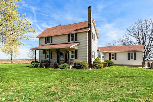 traditional-style house with a front yard, a porch, and a chimney
