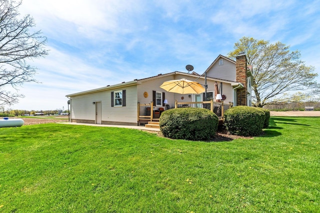 back of house with a wooden deck, a lawn, and a chimney