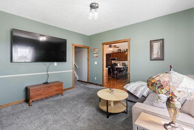 carpeted living room with stairway, a textured ceiling, a ceiling fan, and baseboards