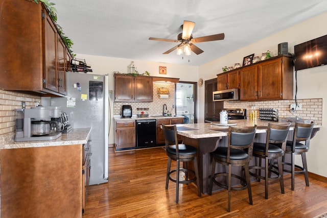kitchen with stainless steel appliances, a peninsula, a sink, tasteful backsplash, and a ceiling fan