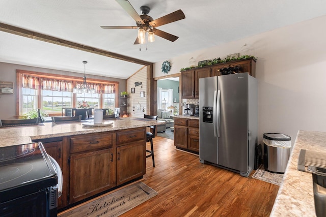 kitchen featuring dark wood-style floors, stainless steel fridge, vaulted ceiling with beams, pendant lighting, and ceiling fan