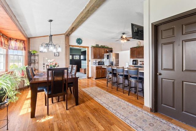 dining room with lofted ceiling with beams, light wood-style floors, and ceiling fan with notable chandelier