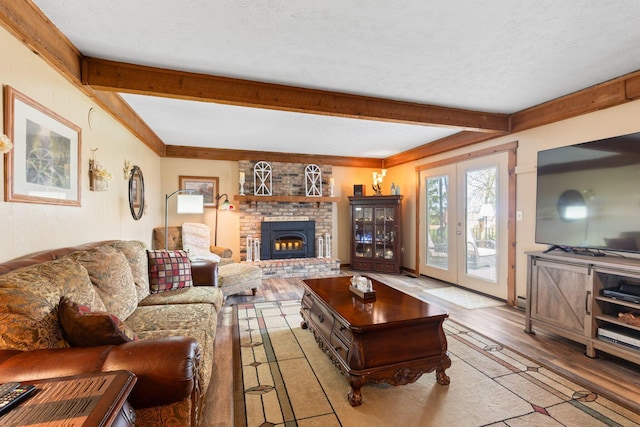 living room with a brick fireplace, wood finished floors, beam ceiling, and a textured ceiling