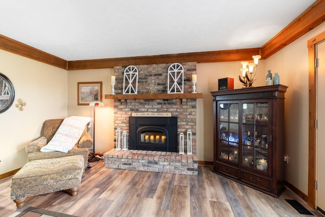 living room featuring visible vents, baseboards, wood finished floors, crown molding, and a fireplace