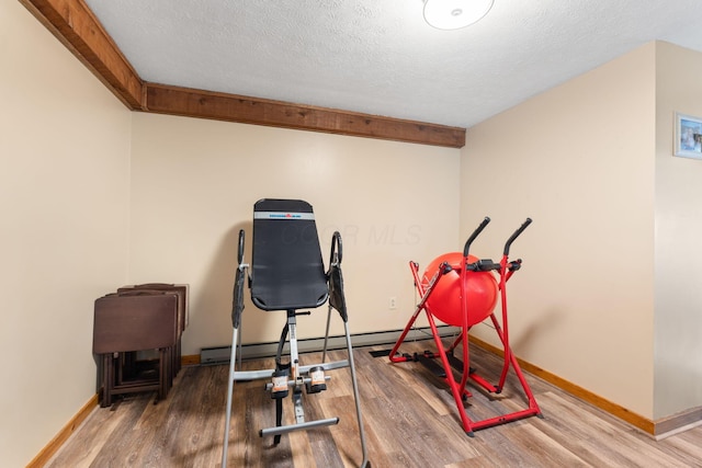 exercise area with baseboards, wood finished floors, and a textured ceiling