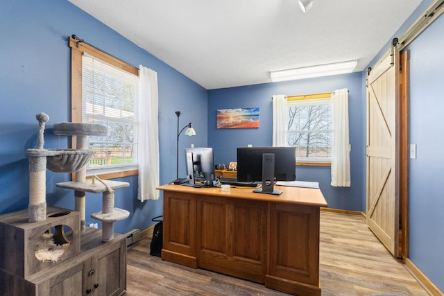 home office featuring a barn door, baseboards, wood finished floors, and a baseboard radiator