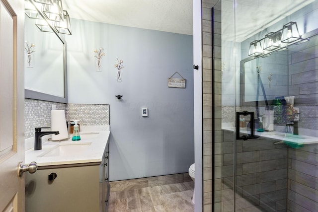 bathroom featuring a shower stall, toilet, tasteful backsplash, and vanity