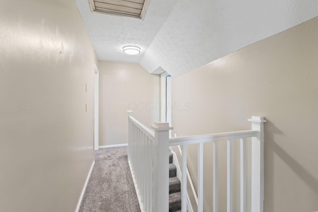 corridor with carpet, visible vents, an upstairs landing, baseboards, and a textured ceiling