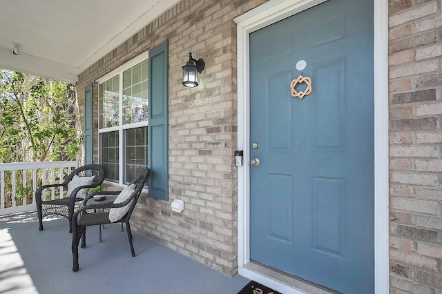 property entrance with brick siding and covered porch