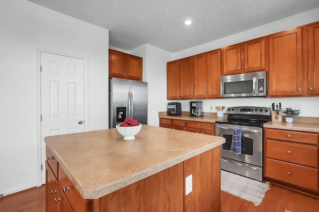 kitchen with stainless steel appliances, a kitchen island, brown cabinetry, and dark wood finished floors