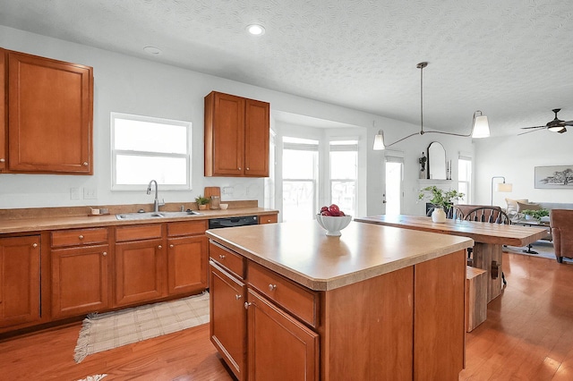 kitchen featuring light wood-type flooring, a textured ceiling, a sink, and brown cabinets