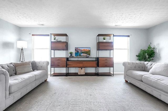 living room with a textured ceiling, visible vents, and baseboards