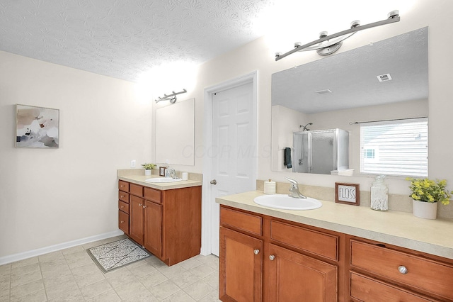 bathroom with a textured ceiling, vanity, a stall shower, and visible vents