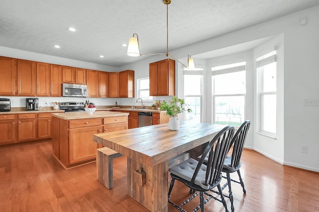 kitchen with recessed lighting, a sink, light wood-type flooring, a center island, and appliances with stainless steel finishes