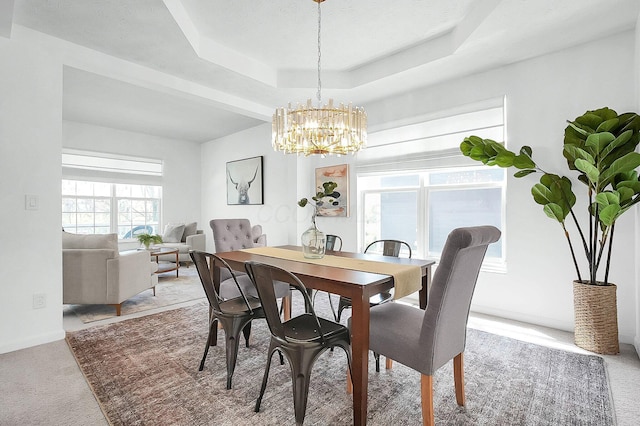carpeted dining space featuring an inviting chandelier and a raised ceiling