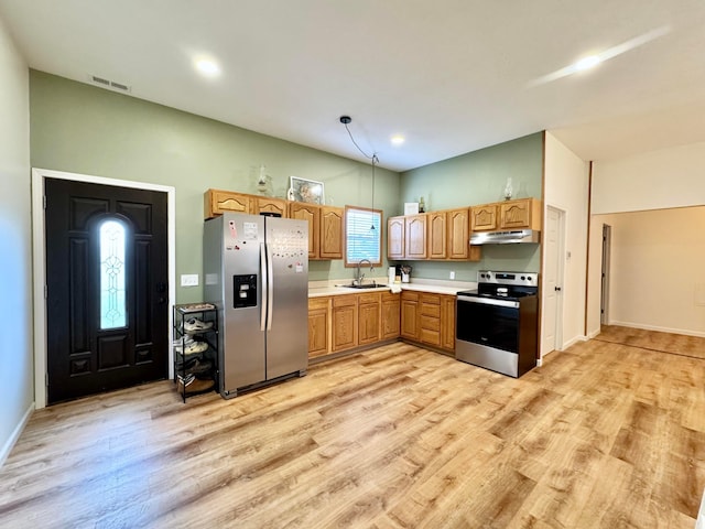 kitchen with stainless steel appliances, a sink, light wood-style floors, light countertops, and under cabinet range hood