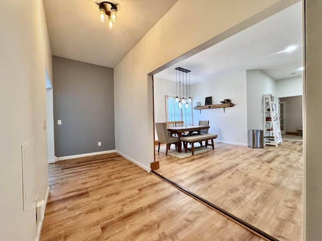 hall with baseboards, a chandelier, and wood finished floors