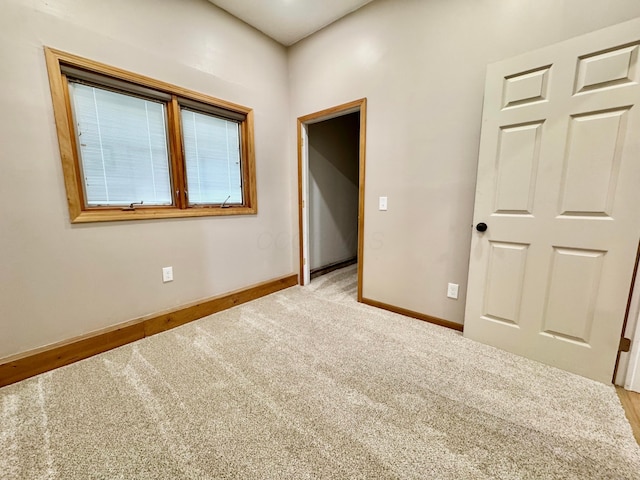 unfurnished bedroom featuring baseboards and light colored carpet