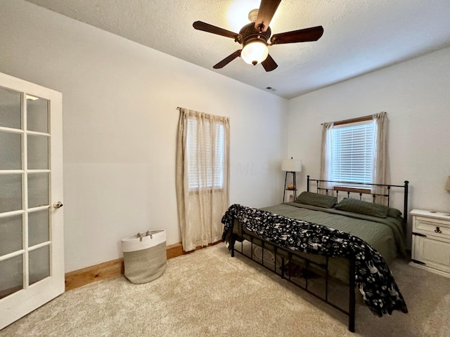 carpeted bedroom with a textured ceiling and a ceiling fan