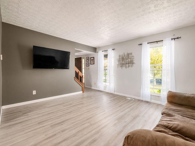 5407 Davidson Rd, Hilliard, OH 43026 - living room with baseboards, a textured ceiling, light wood-style flooring, and stairway