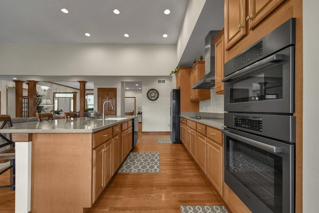 12372 Brook Forest Cir NW, Pickerington, OH 43147 - kitchen with freestanding refrigerator, wall chimney exhaust hood, multiple ovens, a kitchen island with sink, and a sink