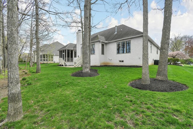 12372 Brook Forest Cir NW, Pickerington, OH 43147 - rear view of property with a sunroom, a chimney, stucco siding, and a lawn