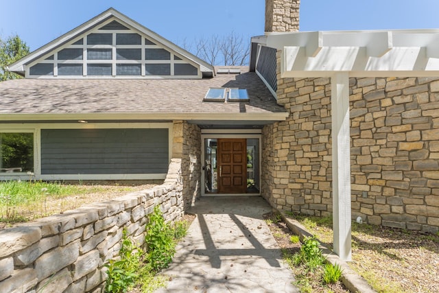 view of front of house with stone siding, a chimney, and roof with shingles