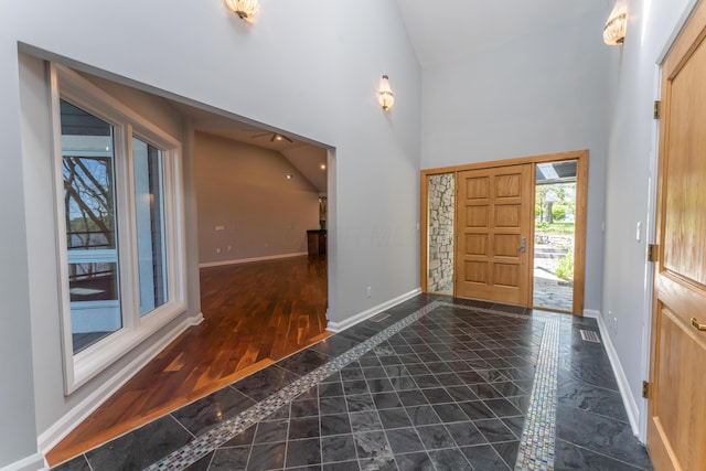 entryway with baseboards, wood finished floors, visible vents, and high vaulted ceiling