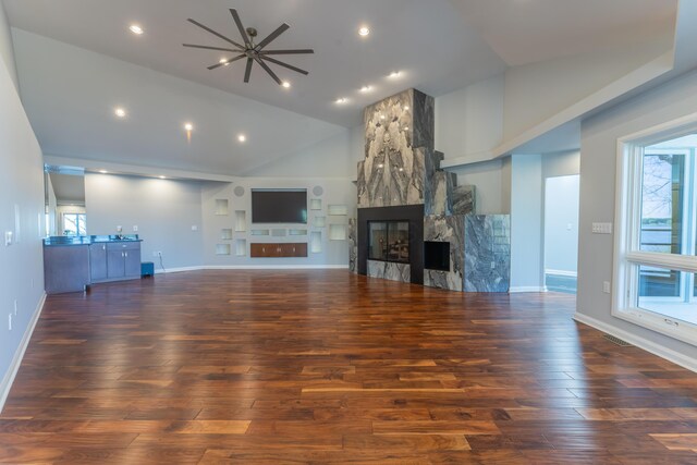 unfurnished living room with visible vents, ceiling fan, wood finished floors, and a large fireplace