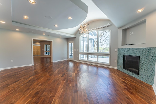 unfurnished living room featuring vaulted ceiling, a tile fireplace, baseboards, recessed lighting, and dark wood-type flooring