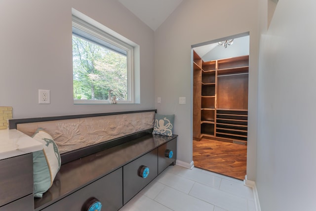 interior space featuring baseboards, an inviting chandelier, light tile patterned floors, and lofted ceiling