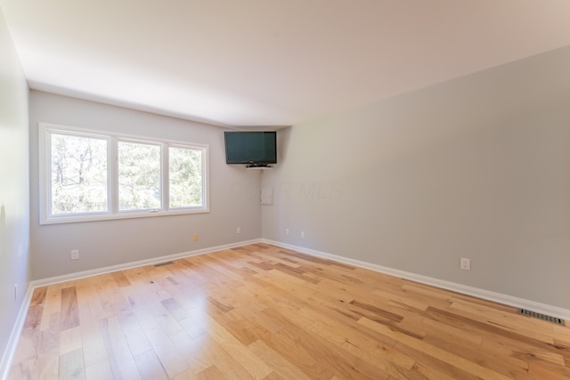 spare room with baseboards, light wood-style flooring, and visible vents