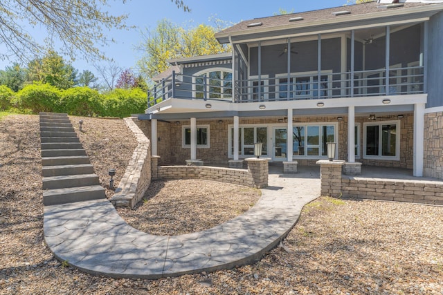 back of property featuring a patio, stone siding, stairs, and a sunroom