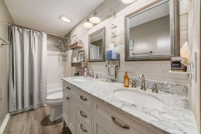 full bath with double vanity, toilet, wood finished floors, and a sink