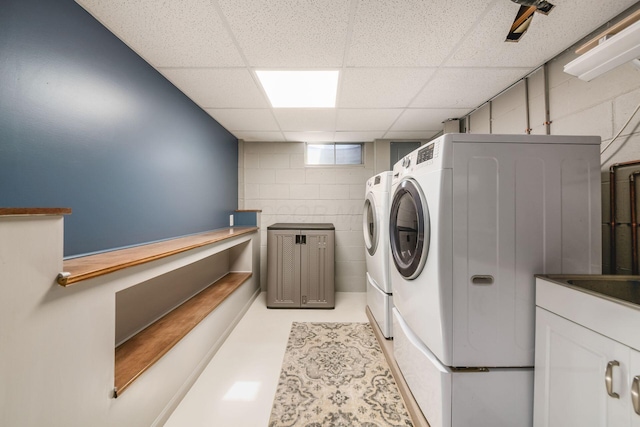 clothes washing area featuring laundry area, concrete block wall, and independent washer and dryer