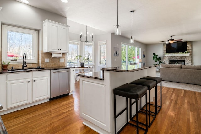478 Riverbend Ave, Powell, OH 43065 - kitchen with a sink, ceiling fan with notable chandelier, wood finished floors, dishwasher, and a fireplace