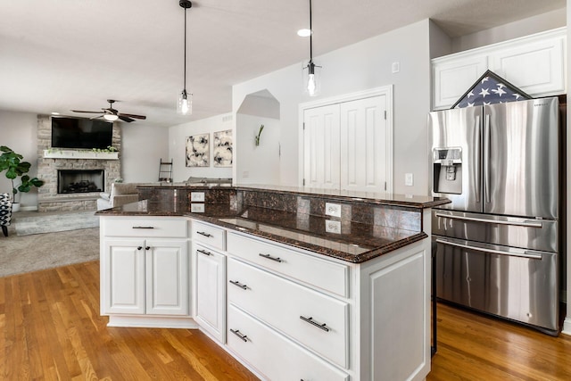 478 Riverbend Ave, Powell, OH 43065 - kitchen with stainless steel fridge, wood finished floors, ceiling fan, a stone fireplace, and hanging light fixtures