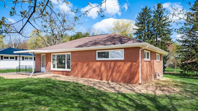 back of house featuring brick siding and a yard