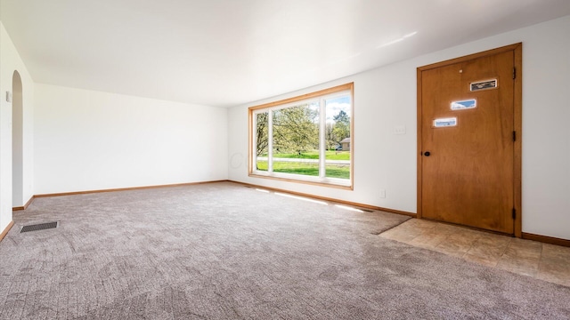 interior space with baseboards, arched walkways, visible vents, and carpet