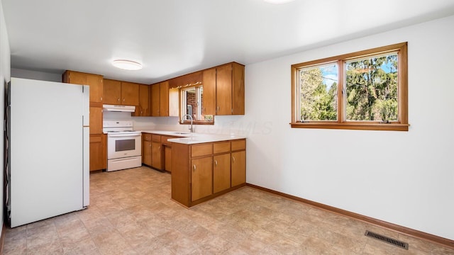 kitchen with brown cabinetry, visible vents, a sink, and white appliances