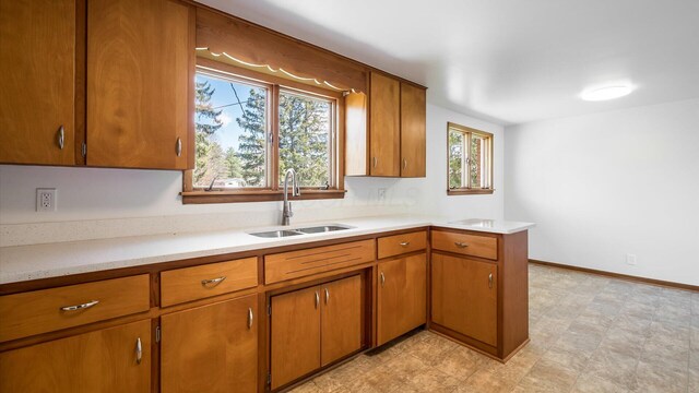 kitchen featuring brown cabinets, light countertops, light floors, and a sink