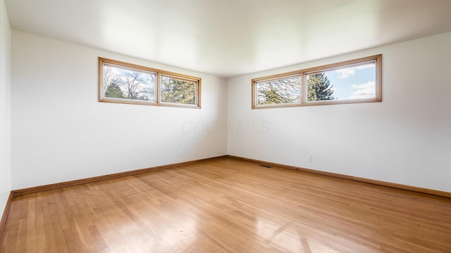 empty room with baseboards and light wood-style floors