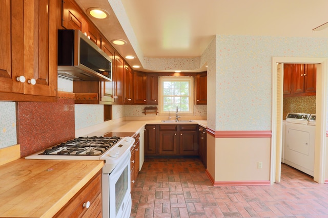 115 E Wheeling St, Lancaster, OH 43130 - kitchen featuring white gas range, stainless steel microwave, brick patterned flooring, a sink, and decorative backsplash